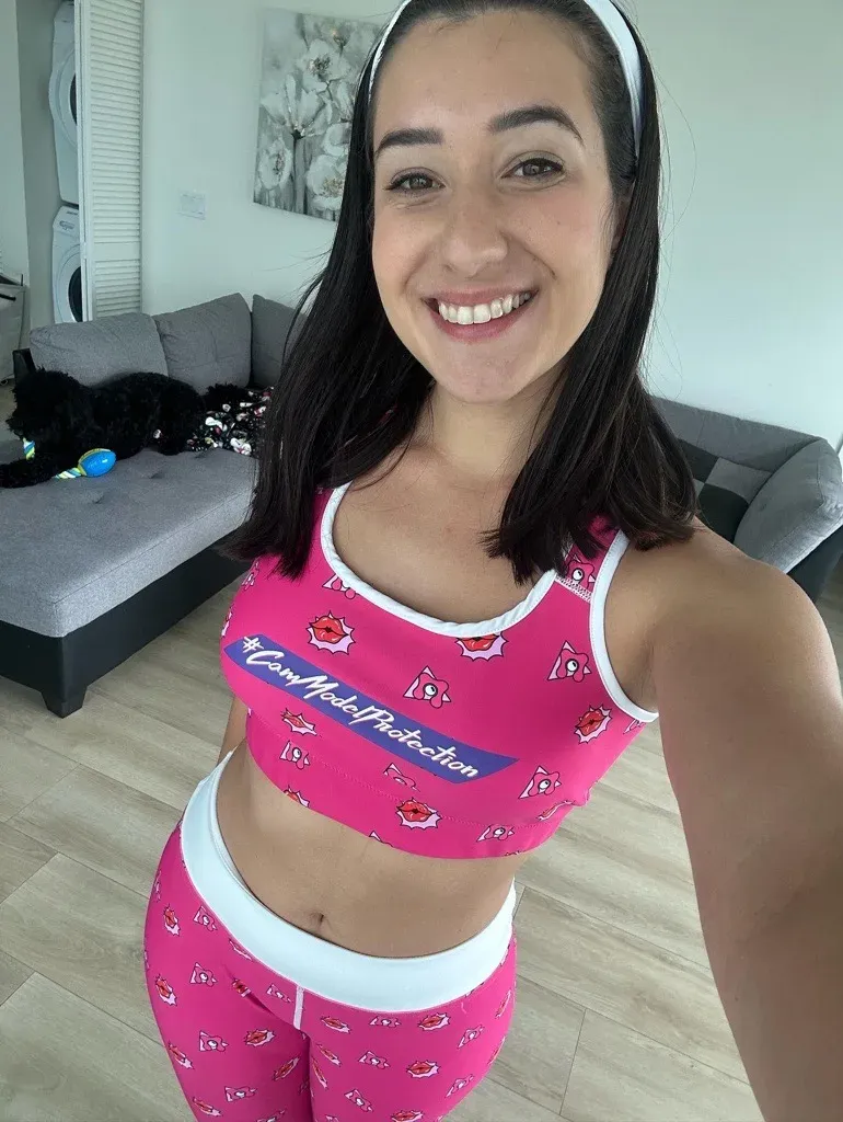 Desy Gato taking a selfie in a pink Cam Model Protection sports bra